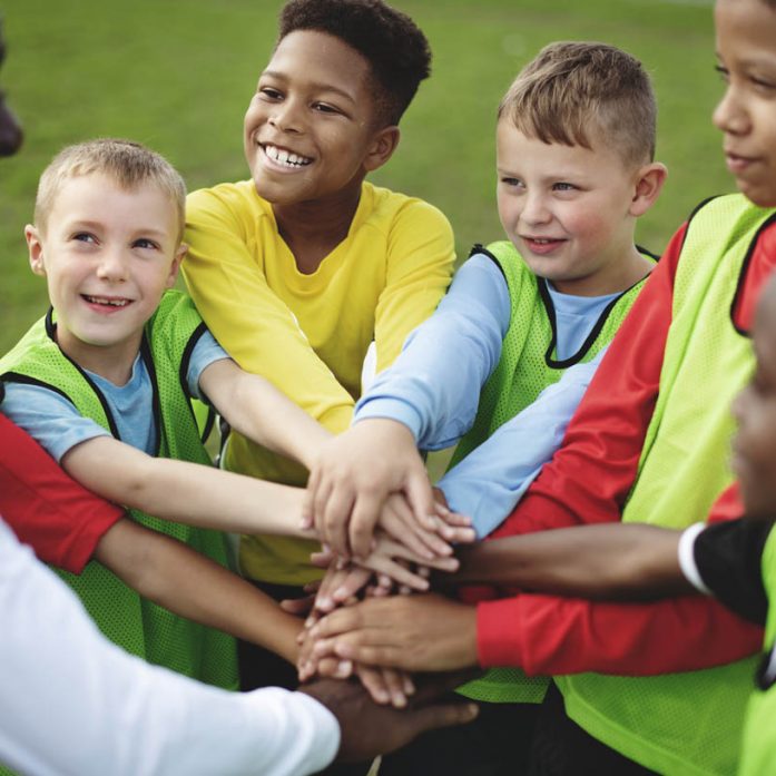 Junior football team stacking hands before a match