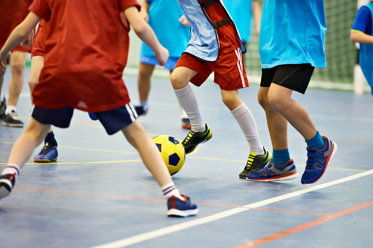 Children playing soccer indoors