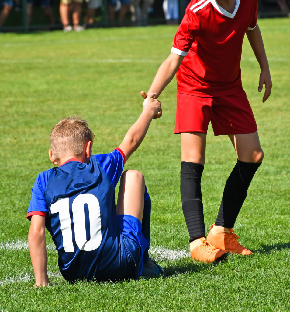 Primary School pupil showing good sportsmanship by helping an opponent